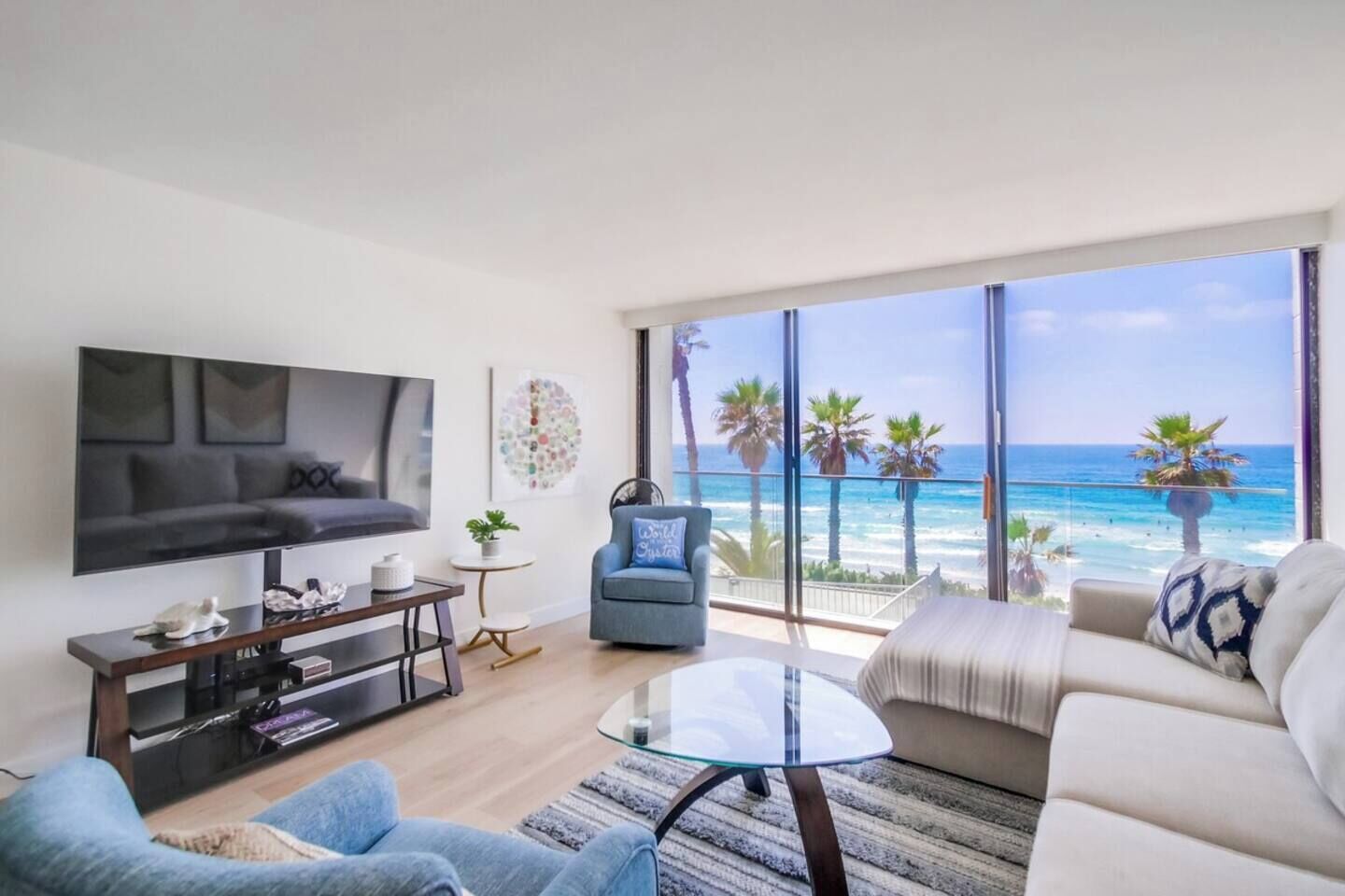 Un soggiorno moderno con una grande TV, un divano, un tavolino da caffè e vista sull'oceano.