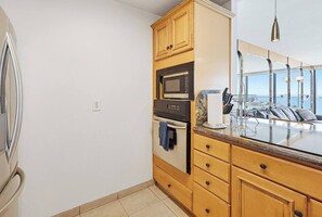 Een moderne keuken met houten kastjes, een ingebouwde oven, magnetron en een groot raam met uitzicht op een prachtig landschap.