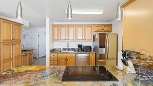 A modern kitchen with wooden cabinets, stainless steel appliances, and a marble countertop. - New photos! Oceanfront condo with parking and pool (San Diego)