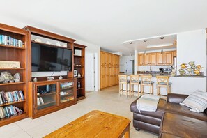 Een woonkamer met een houten tv-meubel, een televisie en een bruine leren bank.