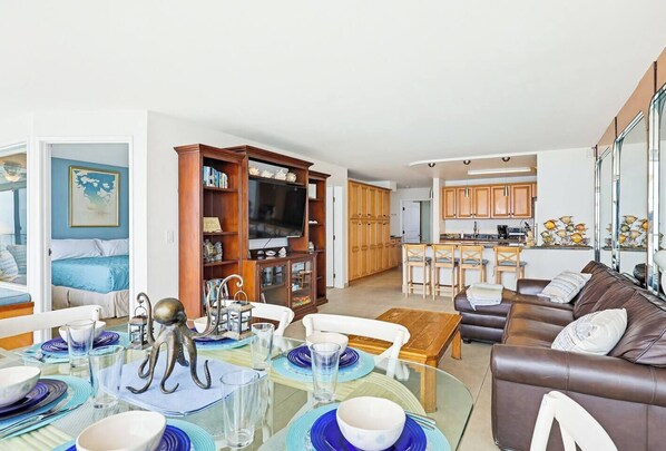 A modern living room with a dining area, a kitchen, and a bedroom.