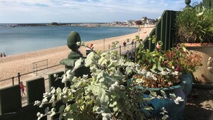 Vista costera con una playa arenosa, un paseo marítimo y plantas en macetas.