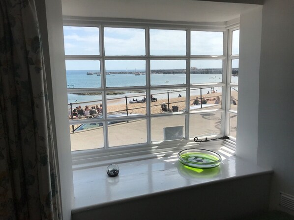 A bay window with a view of a beach and boats. - Cottage on the Beach (Lyme Regis)