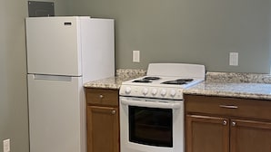 Una cocina con refrigerador, estufa, horno y armarios de madera.