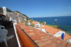 A terrace with a view of the sea, white buildings, and a hillside. - Cozy 1bd Oceanfront balcony view and golf cart (Avalon)