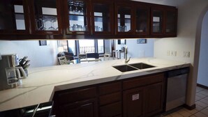 A kitchen with a large island, a double sink, and wooden cabinets.