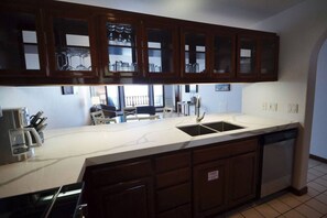 A kitchen with a large island, a double sink, and wooden cabinets. - Hamilton Cove Oceanfront view 2bd with golf cart (Avalon)