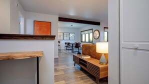 A modern living room with a wooden bench, a sofa, and a table with a lamp. There is a dining area in the background with chairs and a table. - RA605 | Mountain Condo in Resort Setting | Pool and Hot Tubs (Steamboat Springs)