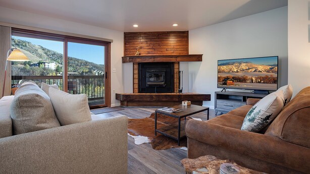 A modern living room with a fireplace, comfortable seating, and a large TV. - RA605 | Mountain Condo in Resort Setting | Pool and Hot Tubs (Steamboat Springs)