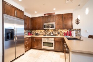 A modern kitchen with wooden cabinets, stainless steel appliances, a tiled backsplash, and a sign reading "BACK AT THE RANCH".