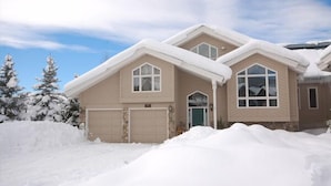 A two-story house with a garage, surrounded by snow.