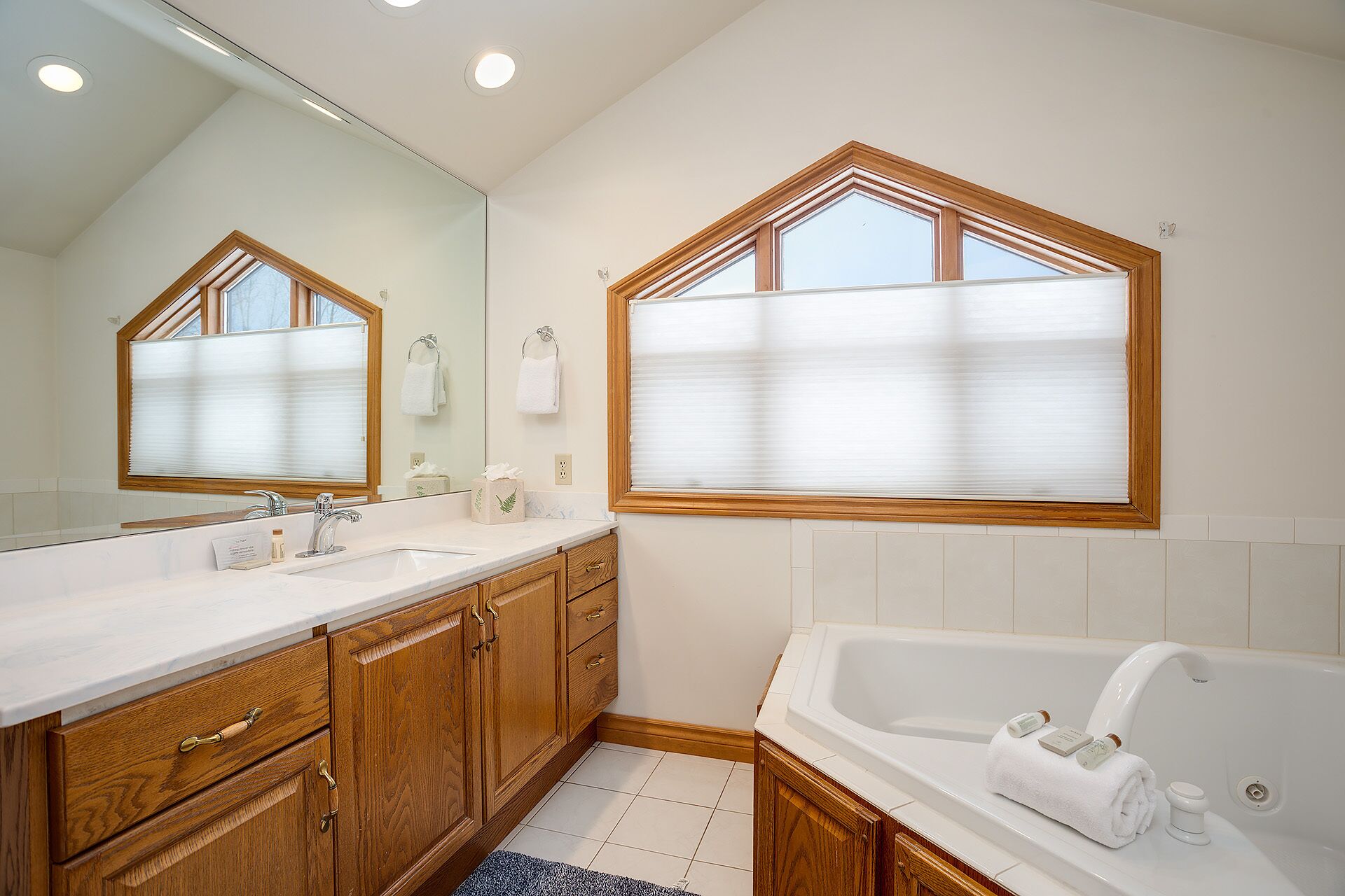 Un baño moderno con tocador doble, muebles de madera, un espejo grande y una bañera independiente.