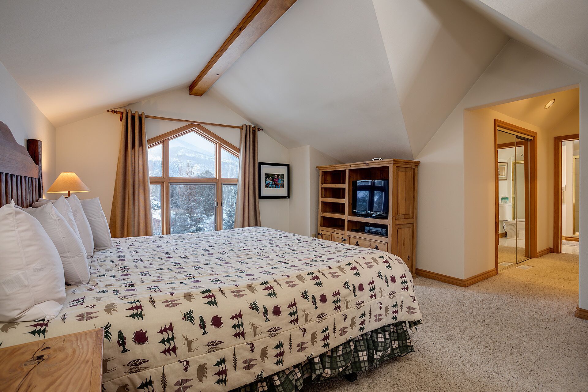 Une chambre avec un grand lit, une télévision et une fenêtre avec des rideaux.