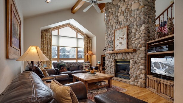 A cozy living room with a stone fireplace, leather sofas, and a television.