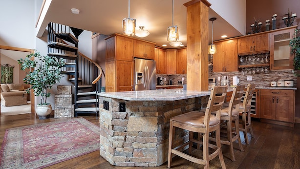 A spacious kitchen with a stone island, wooden cabinets, and a built-in stove.