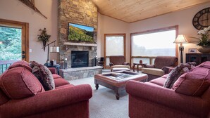 Una sala de estar acogedora con chimenea de piedra, asientos cómodos y amplias ventanas con vistas.
