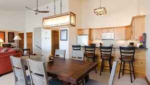 Un coin repas avec une table et des chaises en bois, une cuisine avec des placards en bois et un ventilateur de plafond.