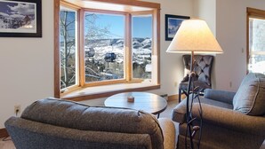 Un salon chaleureux avec une grande fenêtre donnant sur un paysage enneigé et offrant une vue magnifique.