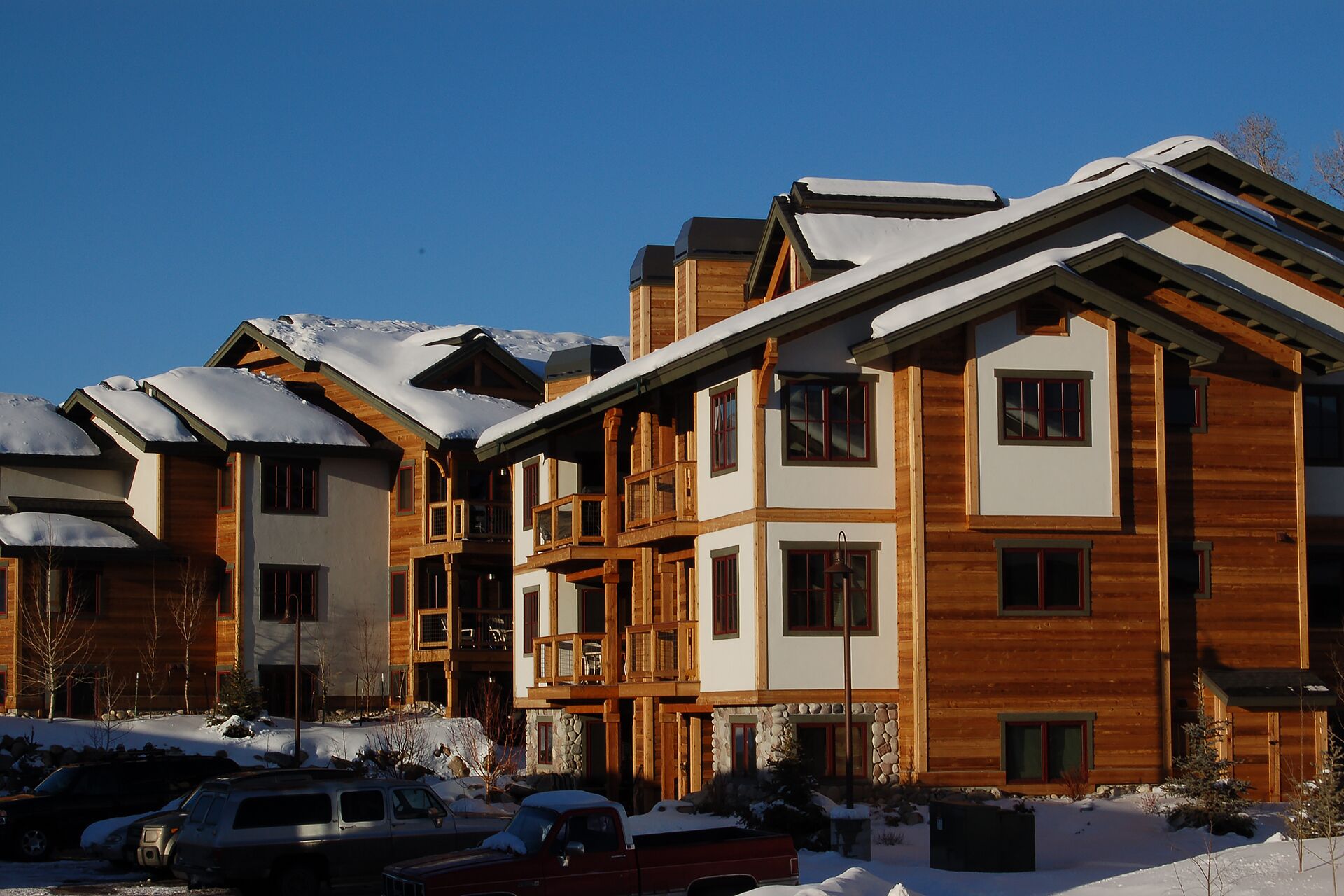 Ein mehrstöckiges Holzgebäude mit Balkonen und schneebedeckten Dächern, vermutlich ein Hotel oder Resort.