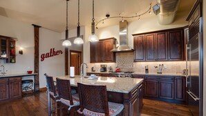 Una cocina amplia con armarios de madera, una isla grande con asientos y electrodomésticos modernos.