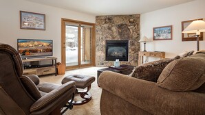 Una sala de estar acogedora con chimenea, muebles de cuero y televisor.