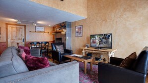 Ein gemütliches Wohnzimmer mit Kamin, Fernseher und Essbereich.