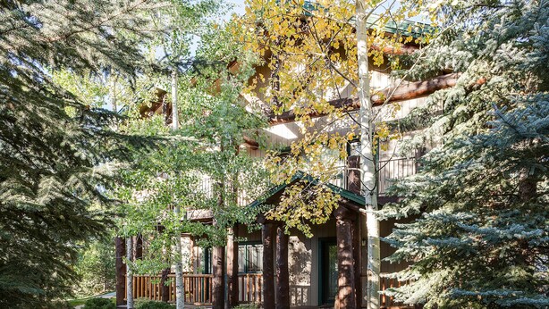 A wooden cabin with a porch, surrounded by dense trees and a stone pathway. - SCK765 | Great Location | Free City Bus | Close to Slopes (Steamboat Springs)