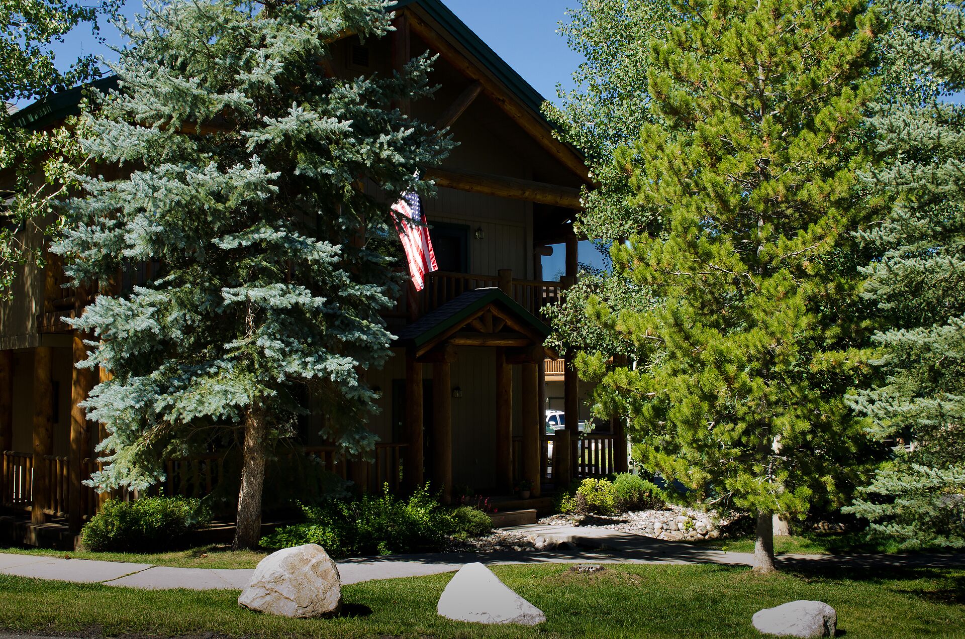 A lodge with a wooden exterior, a porch, and a flag.