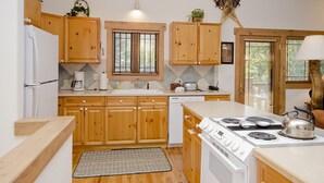 A kitchen with wooden cabinets, a white stove, and a coffee maker. - SCK765 | Great Location | Free City Bus | Close to Slopes (Steamboat Springs)
