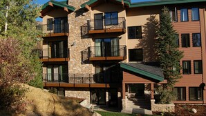 A multi-story building with balconies, stone facade, and a green roof. - SL300 | Modern Penthouse | Views | Pool | Hot Tub | 100 Yds to Lift (Steamboat Springs)