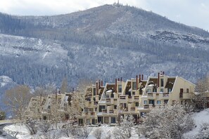 A multi-story hotel with a mountainous backdrop, featuring balconies and a snow-covered landscape. - SW202 | Updated Condo | Great Views | Close to Base Area | A/C (Steamboat Springs)