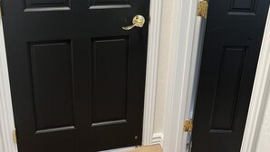 Una puerta negra con picaporte y cerrojo de latón.