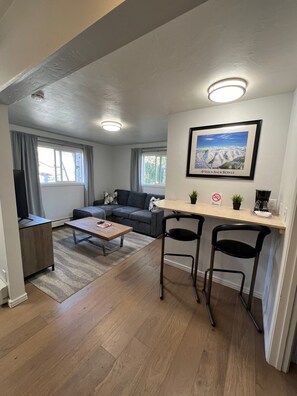 Ein modernes Wohnzimmer mit einer Couch, einem Couchtisch und einem Essbereich mit zwei Stühlen und einem kleinen Tisch.