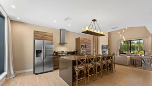 Une cuisine moderne dotée d’un îlot central, d’appareils électroménagers en acier inoxydable et d’un coin repas avec des chaises en bois.
