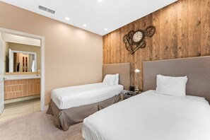 A hotel room with two beds, a wooden accent wall, a clock, and a mirror.