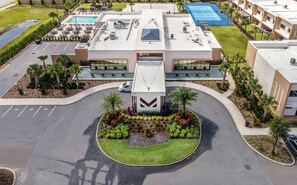 A modern hotel with a central courtyard, a swimming pool, and a tennis court.