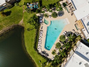 Relax by the pool surrounded by lush greenery and palm trees, with lounge areas for unwinding.