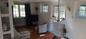 A cozy living room with a sofa, a TV, a lamp, and a plant.