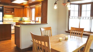 A kitchen with wooden cabinets, a central island, and a dining table with chairs. - Charming Home In Quiet Location Near Downtown Holland! (Holland)