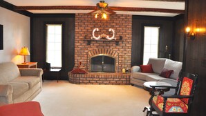 A cozy living room with a brick fireplace, a ceiling fan, and a sofa. - Charming Home In Quiet Location Near Downtown Holland! (Holland)