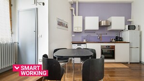 A compact kitchen with modern appliances, a dining area with a table and chairs, and a visible water heater.