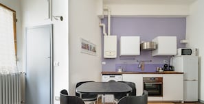 Eine kleine Küche mit modernen Geräten, ein Essbereich mit Tisch und Stühlen sowie ein sichtbarer Warmwasserbereiter.