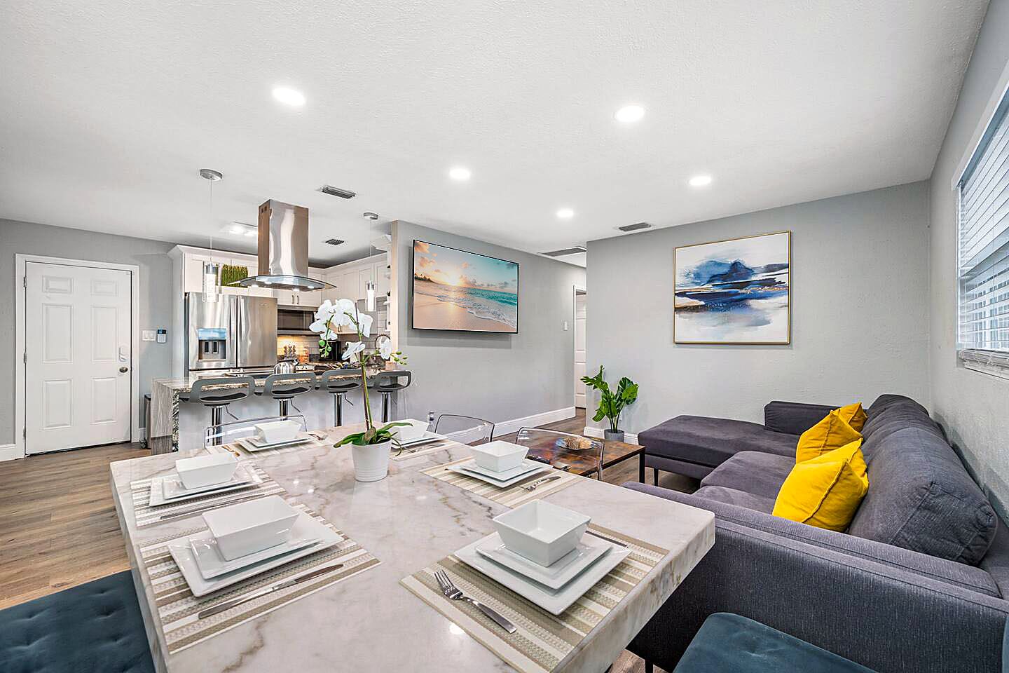 A modern living space with a dining area, kitchen, and seating area.