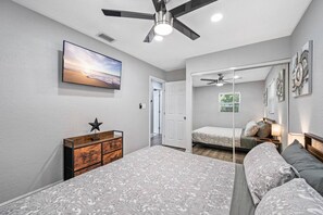 A bedroom with two beds, a ceiling fan, a TV, and a dresser. - Contemporary & Fully Updated Heated Pool Home (Tampa)