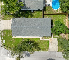 An aerial view of a residential property with a large roof, a swimming pool, and surrounding greenery. - Heated Pool, 5 Min to Busch Gardens | 3BR Sleeps 6, Sunlit Pool Haven (Tampa)