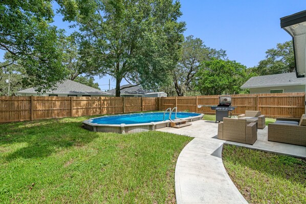 A backyard with a swimming pool, a barbecue grill, and outdoor furniture. - Contemporary & Fully Updated Heated Pool Home (Tampa)