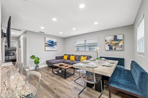 A modern living room with a sofa, coffee table, and dining table. - Heated Pool, 5 Min to Busch Gardens | 3BR Sleeps 6, Sunlit Pool Haven (Tampa)