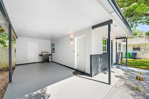 A covered patio area with a grill, a door, and a stone accent wall.