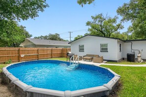 An outdoor swimming pool with a wooden deck and a house in the background. - Contemporary & Fully Updated Heated Pool Home (Tampa)