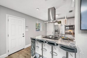 A modern kitchen with a central island, stainless steel appliances, and a bar area with stools.